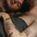Tattooed Man Lying in Bed With Man
